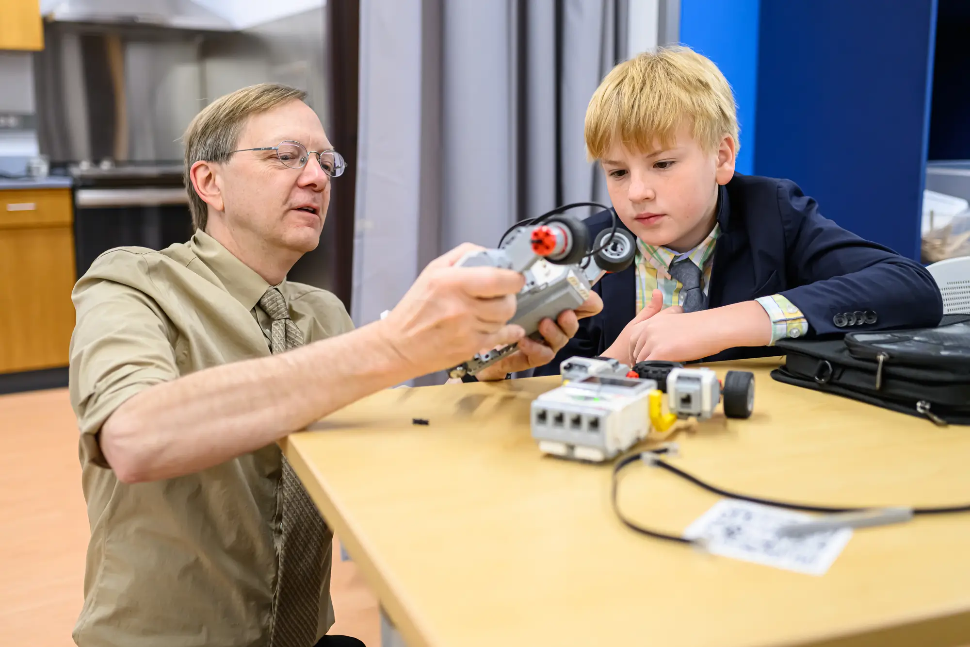 Науковий Боб допомагає учневі середньої школи з робототехнічним проектомВчитель-чоловік допомагає учневі з науковим проектом
